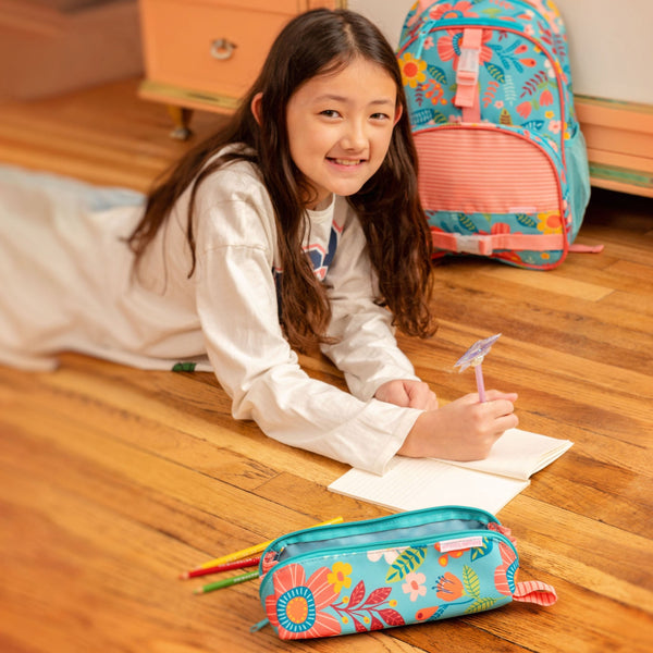 Young girl drawing with pens held in the turquoise floral all over print pencil pouch.