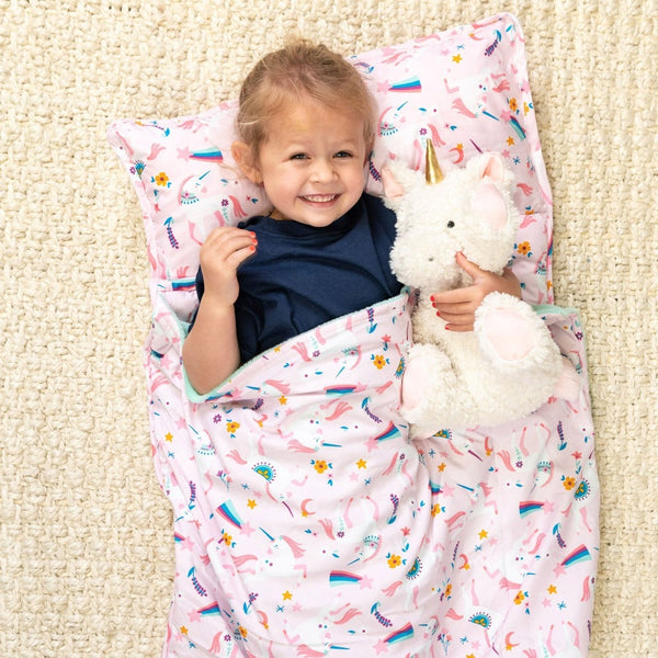 Little girl laying in the unicorn all over print nap mat. 
