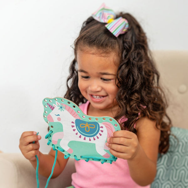 Little girl playing with unicorn lacing card set.