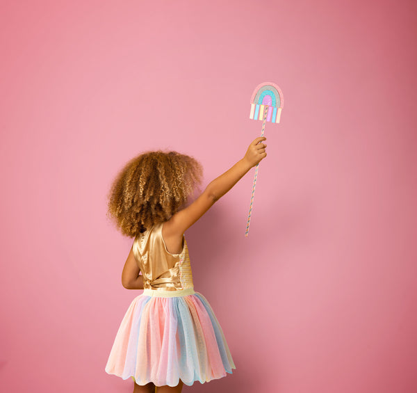 Little girl holding rainbow dress up wand