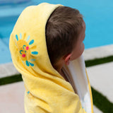 Little boy wrapped in the sunshine beach and bath towel at the pool. 