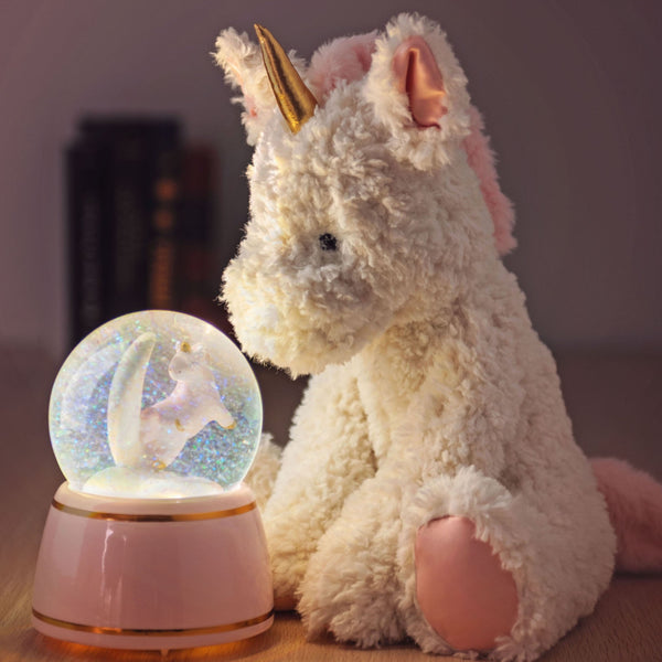 Unicorn cuddle plush doll next to unicorn snow globe