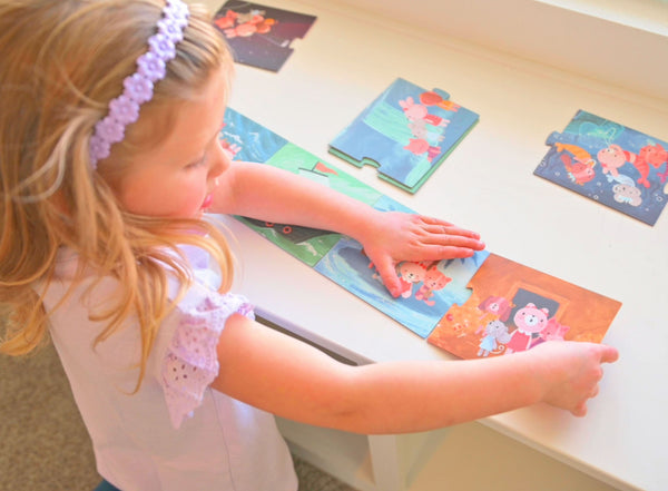 Little girl playing with girl story book puzzle