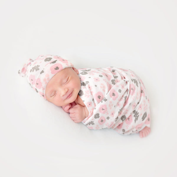 Infant wearing floral beanie and wrapped in floral bamboo blanket.